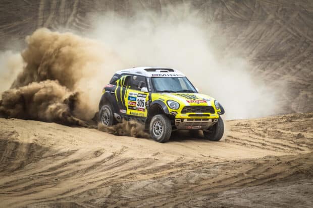A rally raid vehicle kicks up dust as it speeds through a sandy terrain, 2K Desktop Wallpaper