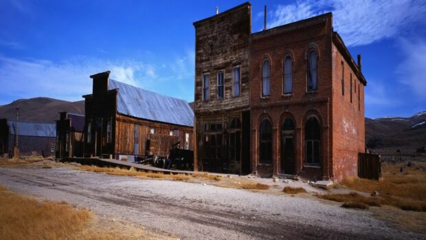 A deserted ghost town with historic wooden and brick buildings under a clear blue sky, HD Desktop Wallpaper