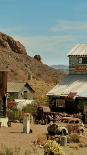 A desert ghost town with old cars and rusty buildings under a clear blue sky, HD Mobile Wallpaper