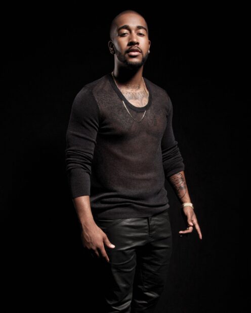 Omarion wears a black sweater and leather pants posing confidently, 2K Desktop Wallpaper
