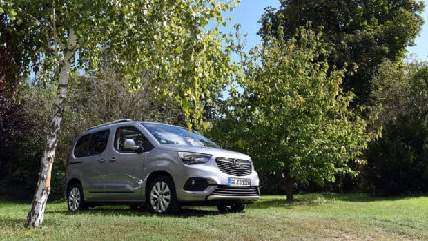 A silver Opel Combo is parked on grass near trees under a clear blue sky, HD Desktop Wallpaper