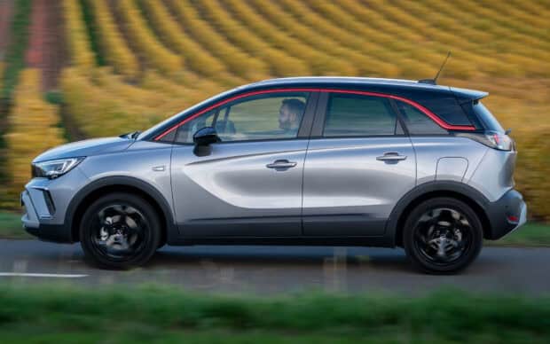 A silver Opel Crossland drives past a yellow field with a man inside the vehicle, HD Desktop Wallpaper