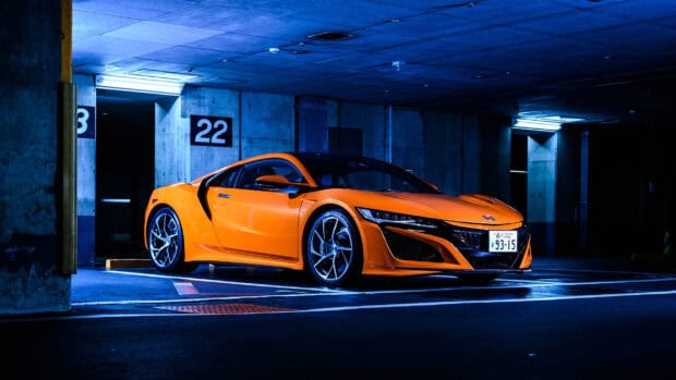 Orange Honda NSX parked in a dimly lit underground garage showing its sharp design, 2K Desktop Wallpaper
