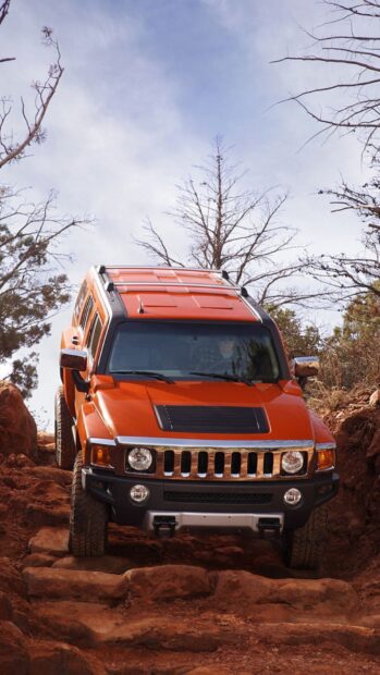 An orange Hummer H3 is navigating a rocky trail surrounded by trees, HD Mobile Wallpaper