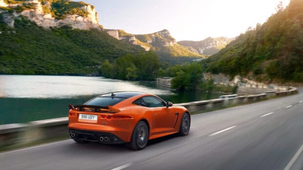 An orange Jaguar F Type is speeding along a scenic road by the lake and mountains, HD Desktop Wallpaper