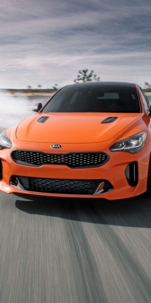 An orange Kia Stinger is captured drifting on a road with smoke behind it, HD Mobile Wallpaper