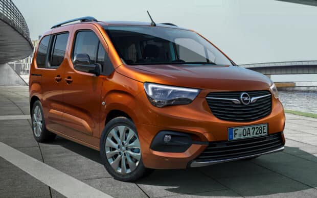 The orange Opel Combo is parked on a paved area next to a river with a bridge in the background, HD Desktop Wallpaper