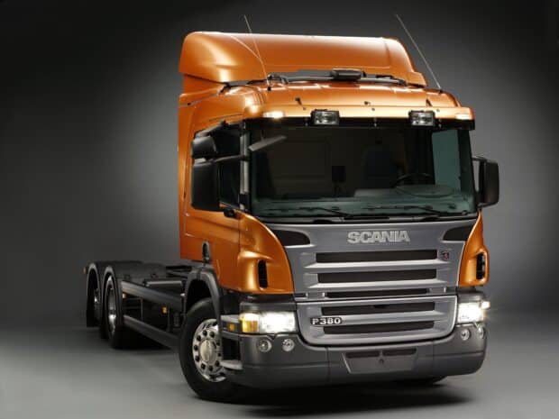 A bright orange Scania truck is displayed from the front with clear headlights and branding, HD Desktop Wallpaper