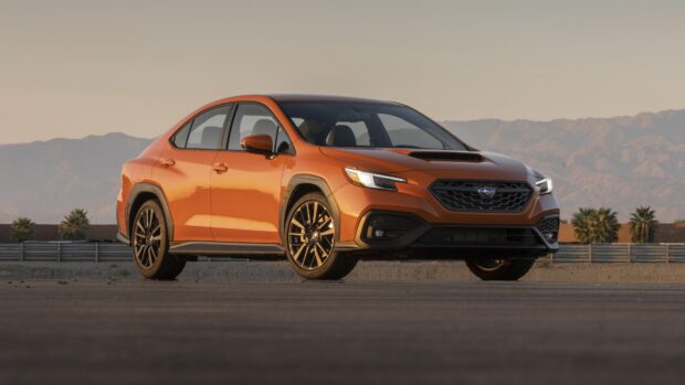 A stylish orange Subaru WRX is parked with mountains in the background during sunset, 4K Desktop Wallpaper
