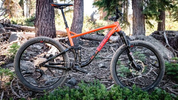 A Marin bike stands on rocky forest ground near trees and greenery, HD Desktop Wallpaper