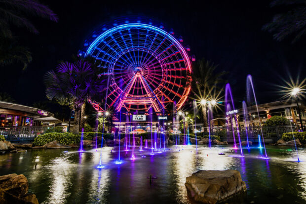 The Orlando Ferris wheel lights up the night sky with colorful fountains in front, HD Desktop Wallpaper