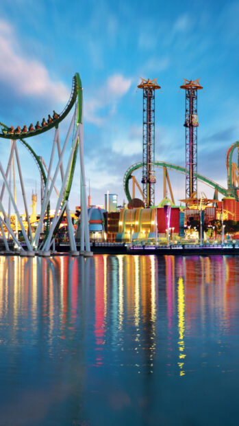 The Orlando wallpapers show colorful amusement park rides reflected in calm water at dusk, HD Phone Wallpaper