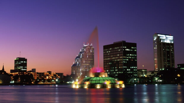 The Orlando fountain glows brightly with city buildings in the background during twilight, 2K Desktop Wallpaper
