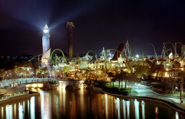 The Orlando cityscape at night reflects on the water with illuminated buildings and rides, 2K Desktop Wallpaper