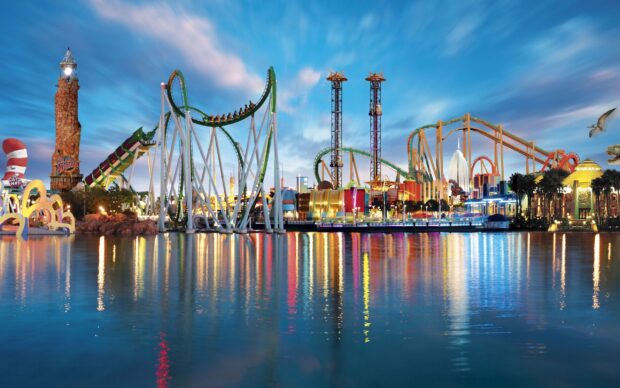 The Orlando Wallpapers capture a vibrant amusement park reflected in water under a dynamic sky, 2K Desktop Wallpaper
