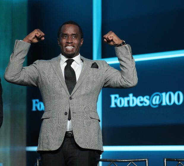 P Diddy Sean Combs smiling and flexing his muscles on stage at a Forbes event, HD Desktop Wallpaper