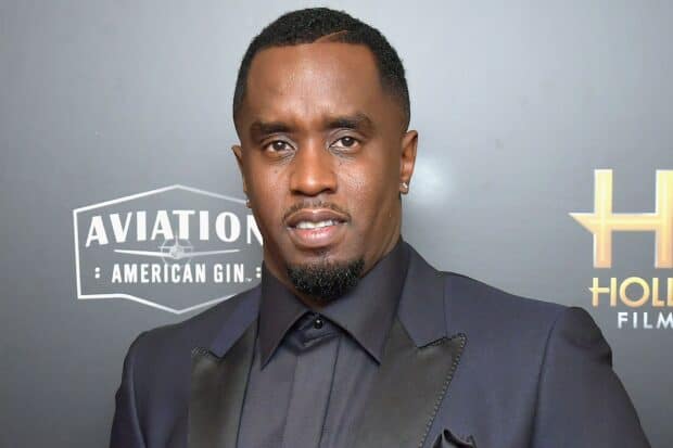 P Diddy Sean Combs smiles wearing a dark suit and earrings at an event, HD Desktop Wallpaper
