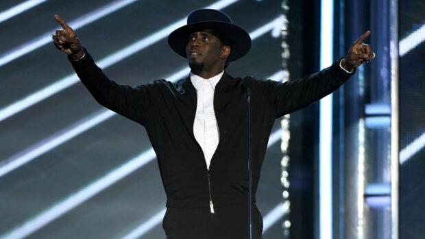 P Diddy Sean Combs is seen pointing upward on stage wearing a black hat and jacket, HD Desktop Wallpaper