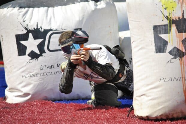 A player aiming with a paintball marker while taking cover during a paintball match, HD Desktop Wallpaper