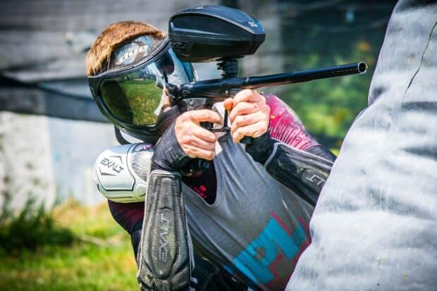 A paintball player is aiming with a marker behind a bunker on the field, HD Desktop Wallpaper