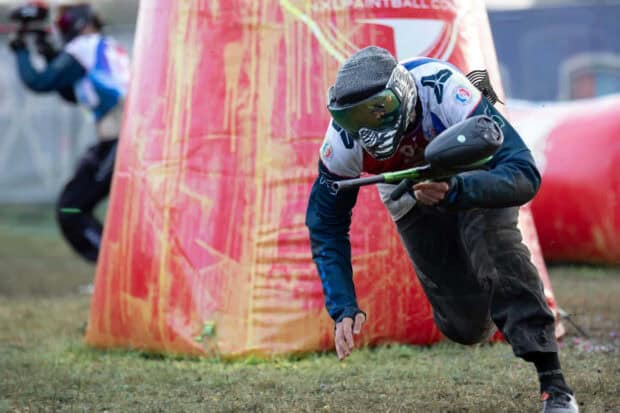 A paintball player in protective gear is diving to avoid a shot on the field, HD Desktop Wallpaper