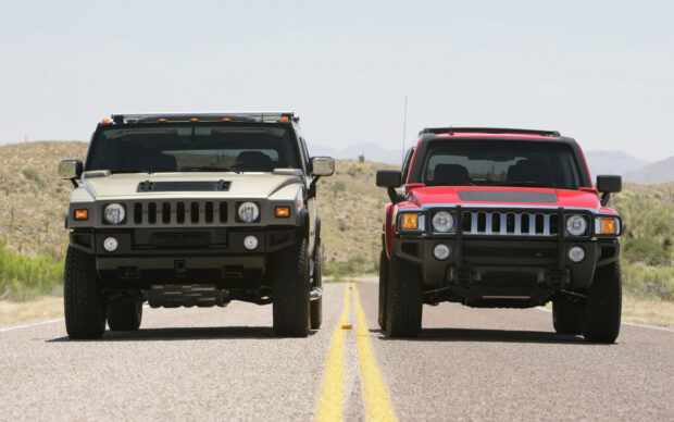 Two Hummer H3 SUVs stand side by side on a rural highway with desert hills in the background, HD Desktop Wallpaper