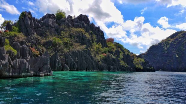 Clear turquoise water surrounds limestone cliffs under blue sky in Palawan, 2K Desktop Wallpaper