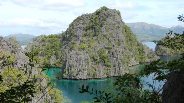 A stunning view of Palawan with emerald waters surrounding rocky cliffs and lush greenery, 2K Desktop Wallpaper