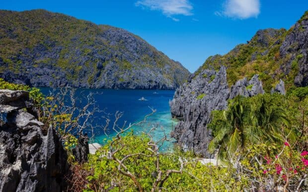 A vibrant coastal scene with clear blue waters and rocky cliffs in Palawan, 2K Desktop Wallpaper