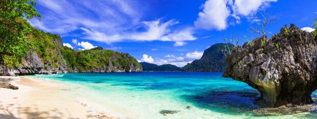 A peaceful tropical beach with clear turquoise water and rocky cliffs in Palawan, 2K Desktop Wallpaper