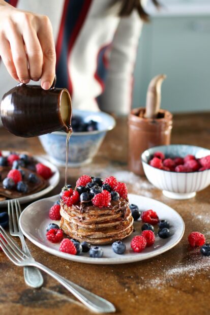 A stack of pancakes topped with fresh raspberries and blueberries being drizzled with syrup, HD Mobile Wallpaper