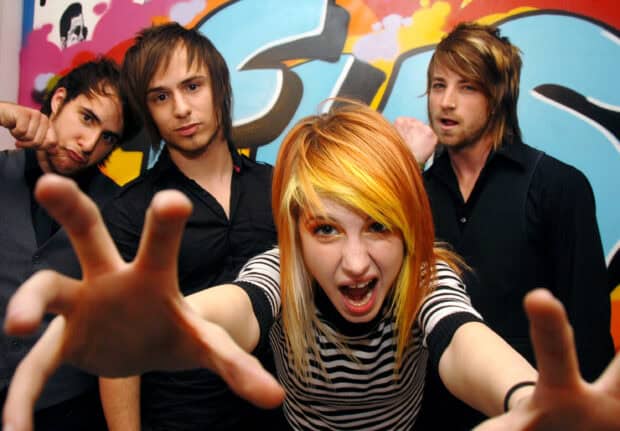 The band Paramore reaches out energetically in front of a colorful wall, 2K Desktop Wallpaper