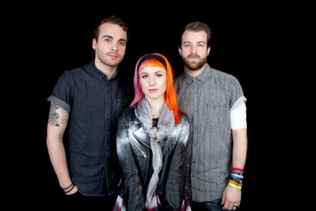 The Paramore band stands together against a black background with colorful hair and casual outfits, HD Desktop Wallpaper