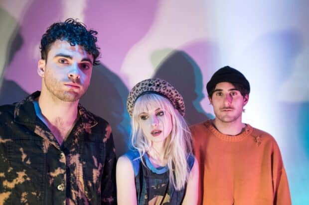 A portrait of Paramore band members standing against a colorful background, HD Desktop Wallpaper