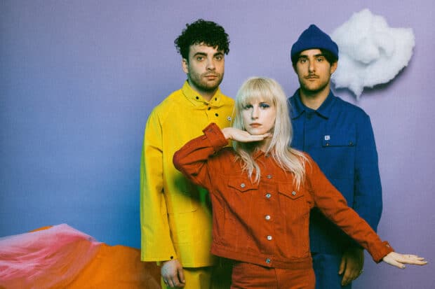 A vibrant photo of Paramore band members wearing colorful clothes against a purple backdrop, HD Desktop Wallpaper