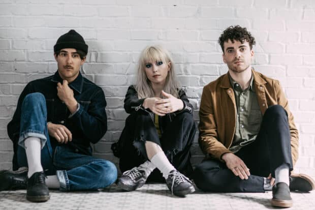 The Paramore band is sitting on the floor against a white brick wall, HD Desktop Wallpaper