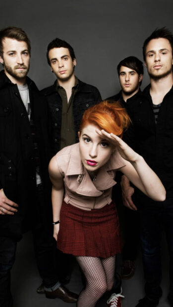 The lead singer of Paramore poses with band members in a studio setting, HD Phone Wallpaper