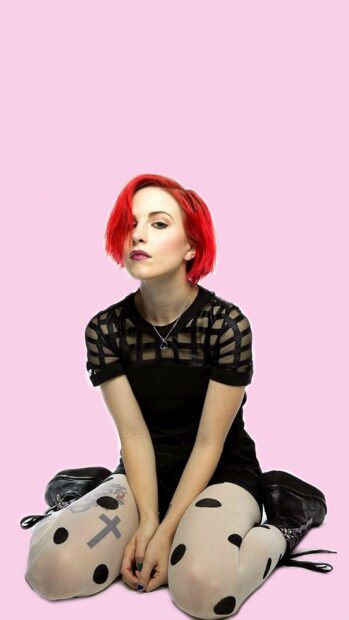 A young woman with red hair sitting wearing black and white clothes featuring tattoo on her leg is showcased in Paramore wallpapers, HD Mobile Wallpaper