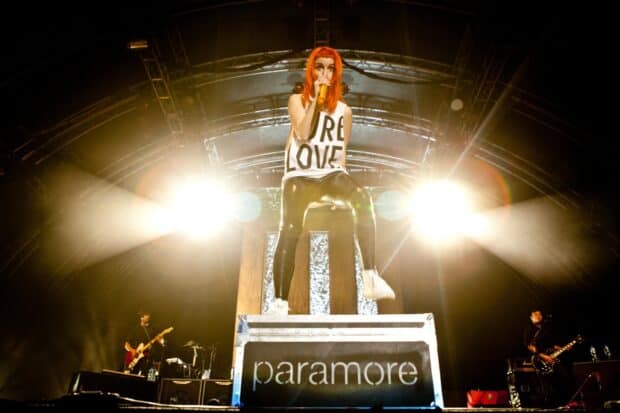 A Paramore lead singer with orange hair performs live on stage with bright lights shining behind, HD Desktop Wallpaper