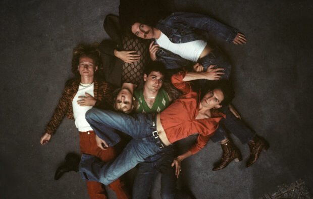 The Parcels band members lie closely together on a dark floor in stylish outfits, HD Desktop Wallpaper