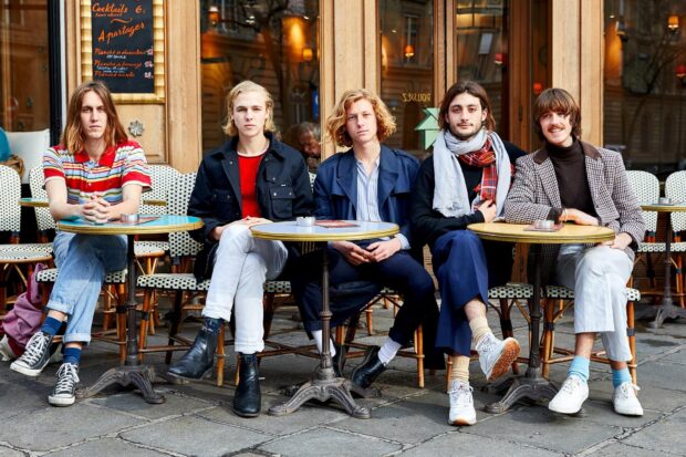 The Parcels band is seated together outside a cafe in a casual setting, HD Desktop Wallpaper