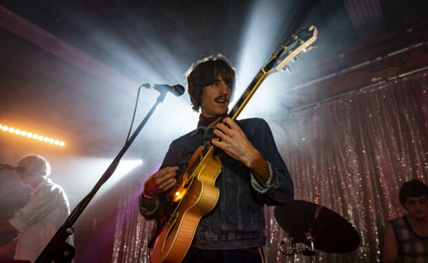 A musician from Parcels Band playing guitar on stage with vibrant lighting, HD Desktop Wallpaper