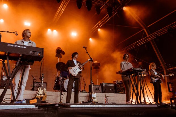 Parcels Band performing live on stage with orange lighting and musical instruments, 2K Desktop Wallpaper