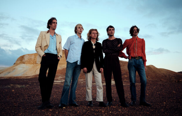 Parcels band members stand together in a rocky desert under a clear sky, HD Desktop Wallpaper
