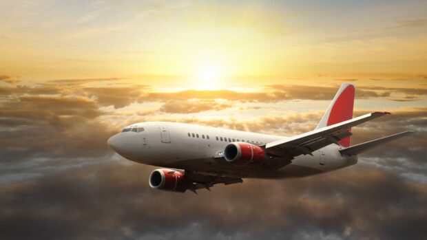 A large aircraft flies above clouds during a golden sunset with red engine covers, HD Desktop Wallpaper