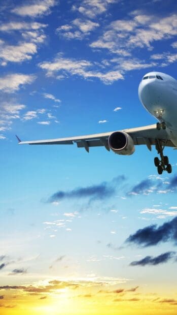 A passenger aircraft is flying in the clear sky at sunset with clouds and sunlight, 2K Mobile Wallpaper