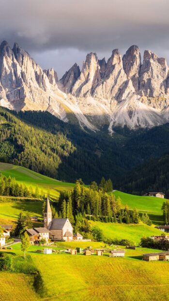 A peaceful village surrounded by lush green fields and towering mountains is shown in village wallpapers, HD Phone Wallpaper