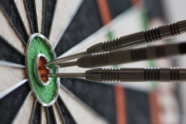 Three darts precisely hit the bullseye on the dartboard in a game of darts, HD Desktop Wallpaper