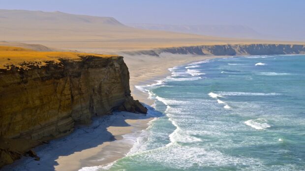 A sandy desert coast with steep cliffs meeting the blue ocean waves in Peru landscapes, HD Desktop Wallpaper