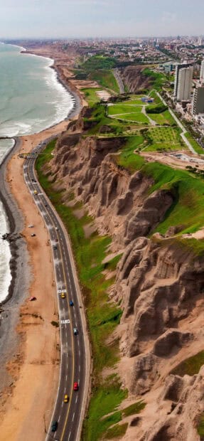 A scenic view of Peru coastal cliffs along the road with green parks and city buildings, 2K Mobile Wallpaper